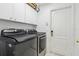 Bright laundry room featuring modern washer and dryer, with white cabinets above the machines at 19129 Lake Audubon Dr, Tampa, FL 33647