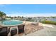 Inviting pool with waterfront views, dock, brick patio with wicker furniture, and serene landscape at 2511 Bay Blvd # B, Indian Rocks Beach, FL 33785