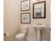 Chic half bathroom featuring a pedestal sink, toilet, and decorative artwork, adding elegance to the space at 20 Outlook Way Blvd # 7, Dunedin, FL 34698