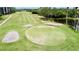 Elevated view of the golf course, highlighting the green, sand traps, and surrounding lush greenery at 2700 Cove Cay Dr # 2B, Clearwater, FL 33760