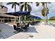 Outdoor patio area featuring tables and chairs under umbrellas, with palm trees and clubhouse in the background at 2700 Cove Cay Dr # 2B, Clearwater, FL 33760