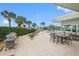 Relaxing outdoor patio featuring dining tables, a grill, and lush greenery with a view of the water and palm trees at 31 Island Way # 1507, Clearwater Beach, FL 33767