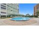 Inviting swimming pool area with brick pavers, lounge chairs, and a view of the surrounding building and lush landscaping at 31 Island Way # 1507, Clearwater Beach, FL 33767