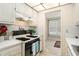 Galley kitchen featuring vintage white cabinetry, black gas range, and open view into the living space at 3128 59Th S St # 206, Gulfport, FL 33707