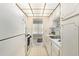 Galley kitchen features white cabinets and appliances with an open view into the living area at 3128 59Th S St # 206, Gulfport, FL 33707