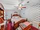 This is a bedroom with floral wallpaper, a ceiling fan, and wood furnishings at 35051 Colony Hills Dr, Zephyrhills, FL 33541