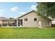 Spacious backyard showcasing a screened lanai, lush lawn, and a neutral-toned exterior with arched windows, ideal for outdoor enjoyment at 4511 Swift Cir, Valrico, FL 33596