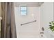 Bright bathroom featuring a white tiled shower/tub with grab bar and window at 4940 Rosedale Ln, Holiday, FL 34690