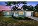 Twilight view of cozy blue single-story home, featuring a one-car garage and freshly painted driveway at 4940 Rosedale Ln, Holiday, FL 34690