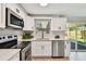 Modern kitchen featuring white shaker cabinets, stainless steel appliances, quartz countertops, and a sliding glass door at 4940 Rosedale Ln, Holiday, FL 34690