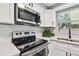 Modern kitchen with stainless steel appliances, quartz countertops, white shaker cabinets, and an electric range at 4940 Rosedale Ln, Holiday, FL 34690