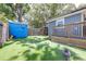 Grassy backyard with wooden fences, a small shed, and a view of the house from the backyard at 5304 Cherry Ave, Seffner, FL 33584