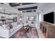 Inviting living room featuring exposed beams, a fireplace, and an open floor plan connecting to the kitchen at 5727 Silverside Pine Ct, Lakewood Ranch, FL 34211