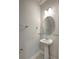 Powder room with pedestal sink, oval mirror, and modern lighting at 6306 Tillandsia Pl, Tampa, FL 33610