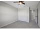 Bright bedroom with gray carpet, a ceiling fan, a closet, and an open doorway at 6306 Tillandsia Pl, Tampa, FL 33610