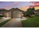 Beautiful home exterior with a driveway, garage, and landscaped lawn under a colorful sky at 6514 Thicket Trl, New Port Richey, FL 34653
