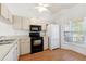 Bright kitchen featuring white cabinetry, black appliances, and a sunlit bay window at 6514 Thicket Trl, New Port Richey, FL 34653