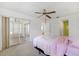 Bright bedroom with ensuite sunroom, fan, and neutral carpet and paint at 6514 Thicket Trl, New Port Richey, FL 34653