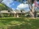 Charming single-story home with dormer windows, a lush lawn, mature trees, and well-maintained landscaping at 8361 Cofield Ln, Spring Hill, FL 34608