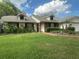 Charming single-story home with dormer windows, a lush lawn, mature trees, and well-maintained landscaping at 8361 Cofield Ln, Spring Hill, FL 34608
