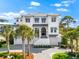 Elegant two-story white home featuring meticulous landscaping, a paved driveway, and charming blue awnings at 885 Seaview Cir # 20, Crystal Beach, FL 34681