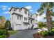 Stunning three-story white home featuring a two-car garage, elegant stairway, and lush landscaping at 885 Seaview Cir # 20, Crystal Beach, FL 34681