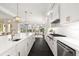 Modern white kitchen with dark wood floors, a spacious island, and stainless steel appliances, perfect for Gathering meals at 885 Seaview Cir # 20, Crystal Beach, FL 34681