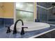 Close up of bathtub with dark hardware and blue tiled accents with a window at 9315 Knightsbridge Ct, Tampa, FL 33647