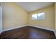 Bedroom features hardwood floors, base trim, yellow walls, and a window for natural light at 9315 Knightsbridge Ct, Tampa, FL 33647