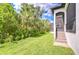 Lush green backyard featuring mature trees, a screened door and steps to the home at 1015 Seagrape Dr, Ruskin, FL 33570