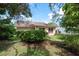 Rear exterior of a house with a well-maintained lawn, lush landscaping, and shade trees at 10516 Mira Vista Dr, Port Richey, FL 34668