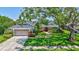Charming single-story home featuring a well-manicured lawn and lush landscaping, complemented by an attached two-car garage at 10825 Christopher Ct, Largo, FL 33774