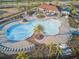 Aerial view of the community pool area, featuring palm trees, lounge chairs, and a modern bath house at 11688 Brighton Knoll Loop, Riverview, FL 33579