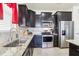 Close-up of a kitchen with stainless steel appliances, granite countertops, and dark wood cabinets for an updated aesthetic at 11688 Brighton Knoll Loop, Riverview, FL 33579