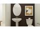 Stylish powder room featuring a pedestal sink, oval mirror and modern wall art at 11845 Sparkling Topaz Cv, Parrish, FL 34219