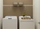 Convenient laundry room with modern washer and dryer, complemented by overhead storage shelf at 11845 Sparkling Topaz Cv, Parrish, FL 34219