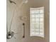 Close-up of shower with glass block window, handheld shower head, grab bar, and tiled walls at 120 Cedarwood Cir # 120, Seminole, FL 33777