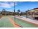 Community shuffleboard court with palm trees, lounge chairs, pool, seating, and blue skies at 120 Cedarwood Cir # 120, Seminole, FL 33777