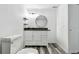 Modern bathroom featuring sleek vanity with dark countertop, floating shelves, and round mirror at 1247 21St St, Sarasota, FL 34234