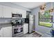 Efficient kitchen boasts white cabinets, granite countertops, and stainless steel appliances, next to a sunlit window at 1278 Mission Cir # 45B, Clearwater, FL 33759