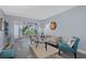 Sunlit living room featuring gray wood floors, a floral sofa, and ample natural light from large windows at 1278 Mission Cir # 45B, Clearwater, FL 33759