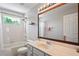 Well-lit bathroom featuring a large mirror, single vanity, and tub with shower at 12935 Solola Way, Trinity, FL 34655
