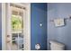 Cozy bathroom with blue walls, a toilet, and a view of the outdoor patio through a glass paneled door at 12935 Solola Way, Trinity, FL 34655