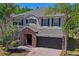 Two-story home featuring a stone-accented entry, dark-stained garage door, and professionally landscaped front yard at 12935 Solola Way, Trinity, FL 34655