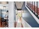 Hallway featuring stairs with black metal railing and a view into a naturally lit kitchen area at 12935 Solola Way, Trinity, FL 34655