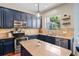 Modern kitchen featuring blue cabinets, stainless steel appliances, an island, and granite countertops at 12935 Solola Way, Trinity, FL 34655