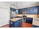 Well-designed kitchen featuring blue cabinets, stainless steel appliances, an island, and beautiful hardwood floors at 12935 Solola Way, Trinity, FL 34655