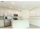 Well-lit kitchen with stainless steel appliances, white cabinets, a breakfast bar, and tile flooring at 13261 Tropical Breeze Way, Hudson, FL 34669