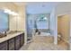 Elegant main bathroom featuring a soaking tub, glass-enclosed shower, and a granite-topped vanity at 13742 Artesa Bell Dr, Riverview, FL 33579