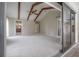 Bright bedroom with vaulted ceiling, exposed beams, carpet floors, and a sliding glass door to the patio at 13906 Captains Reef Ct, Tampa, FL 33624